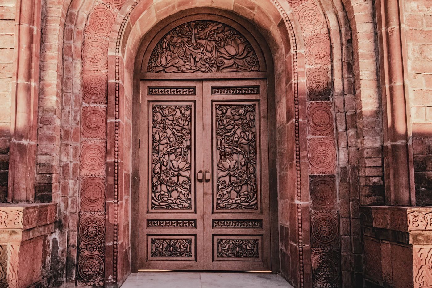 An ornately carved wooden door set within a Mughal red-sandstone archway